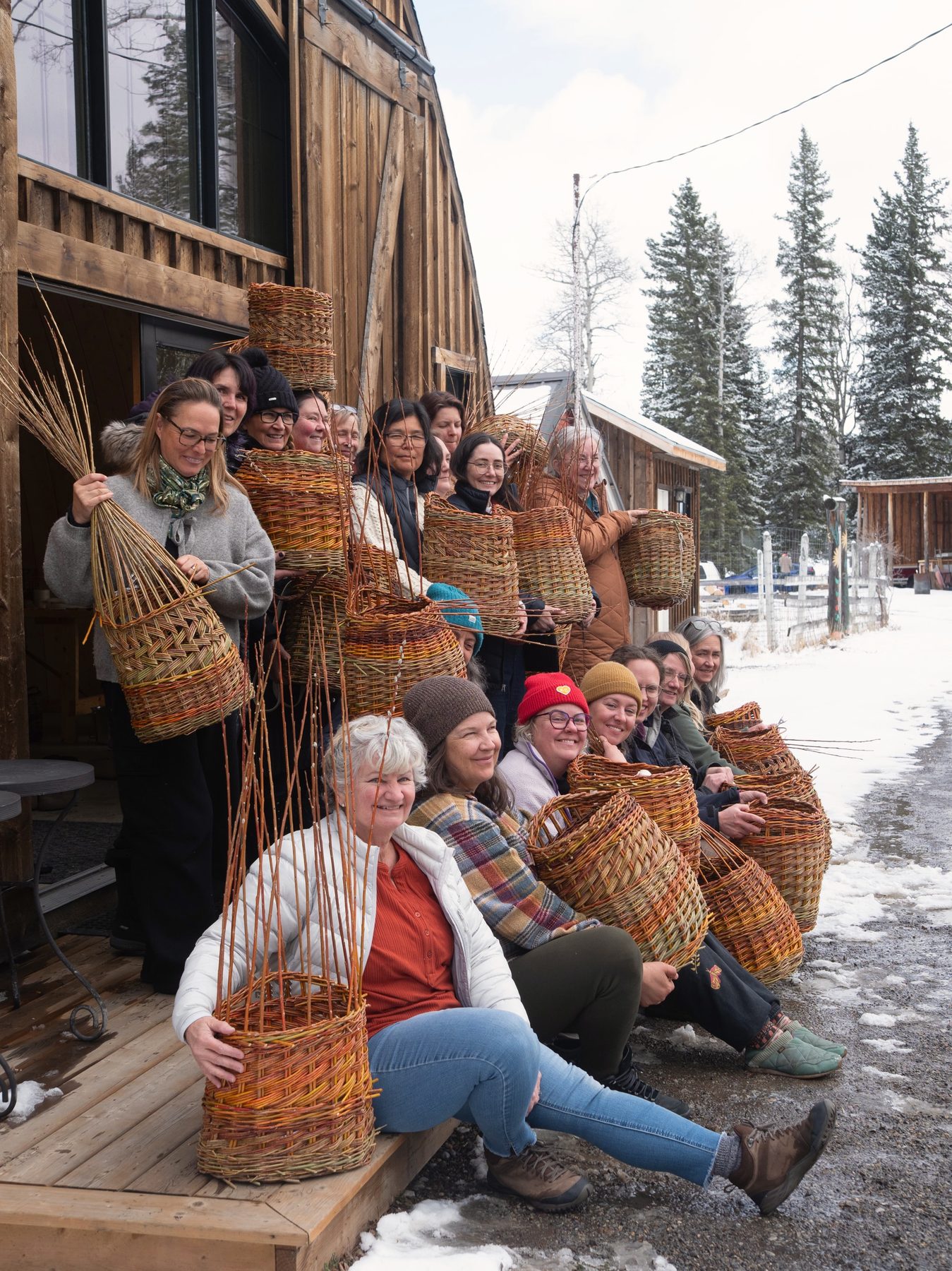 Weavers gathered on the lodge steps at Folk Tree, each holding the willow basket they made