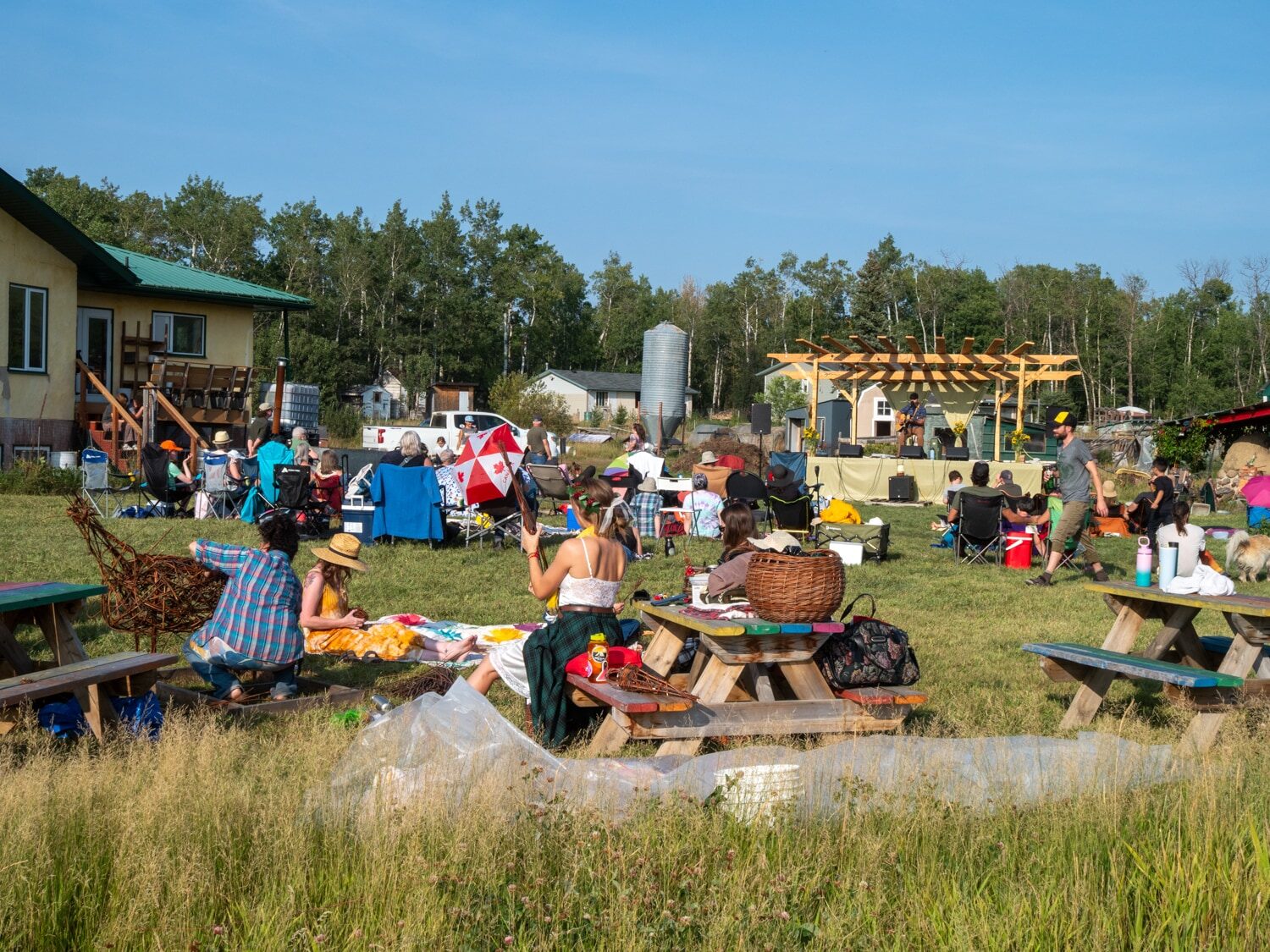 The Good Note Harvest Festival crowd on the farm, with the stage and picnic tables