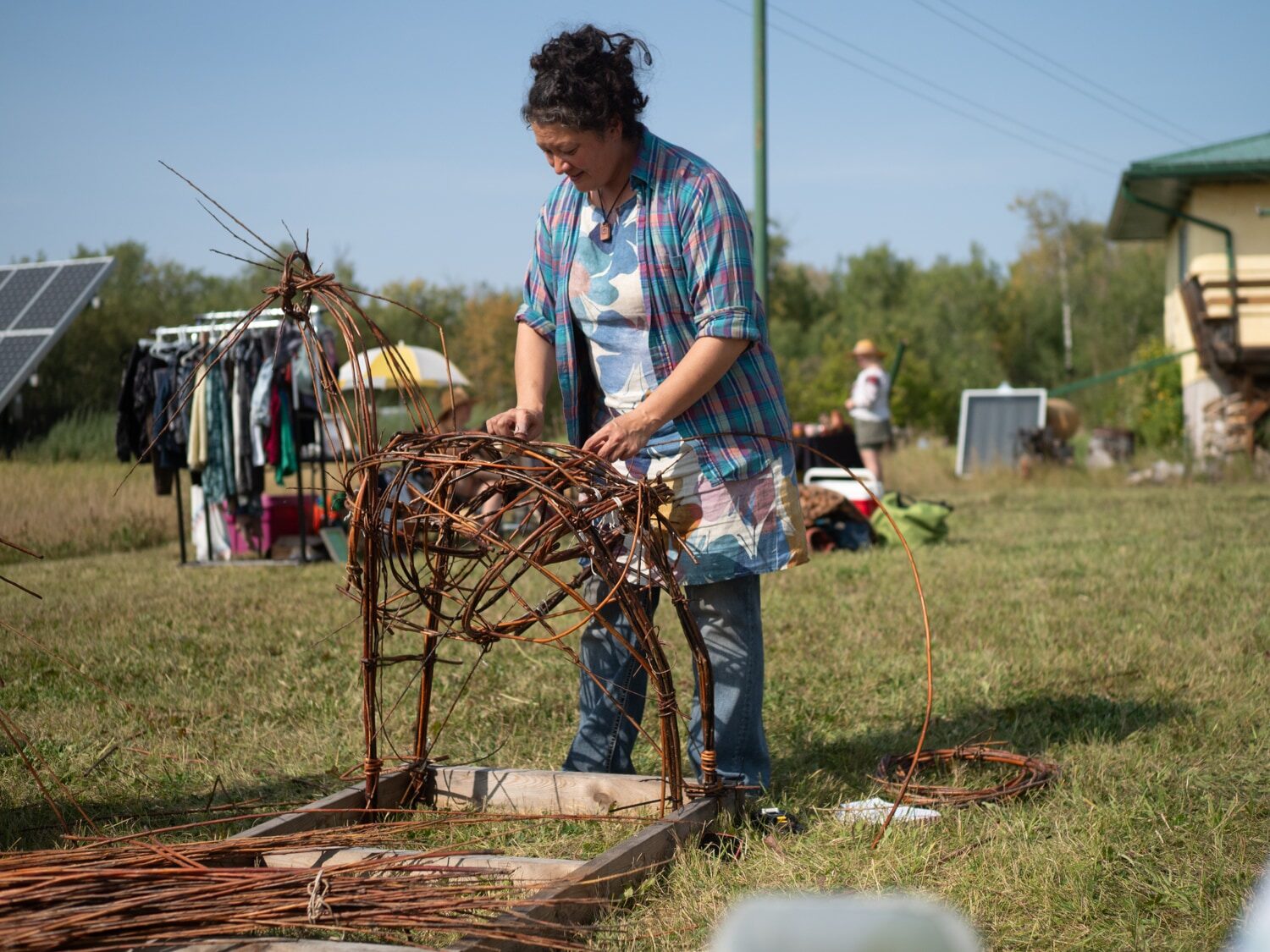 A weaver building the willow goat's frame in daylight