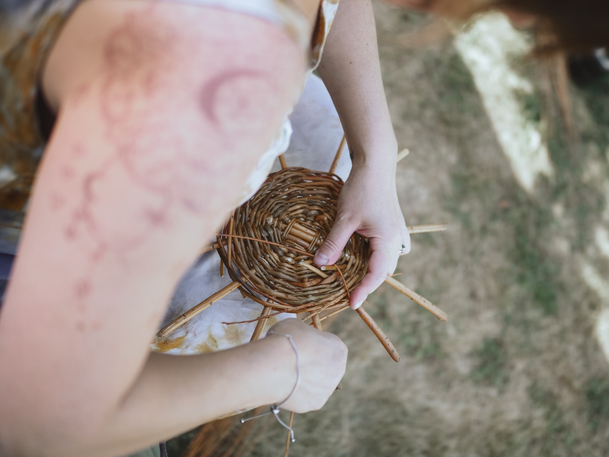 A group weaving large twisted willow baskets together outdoors